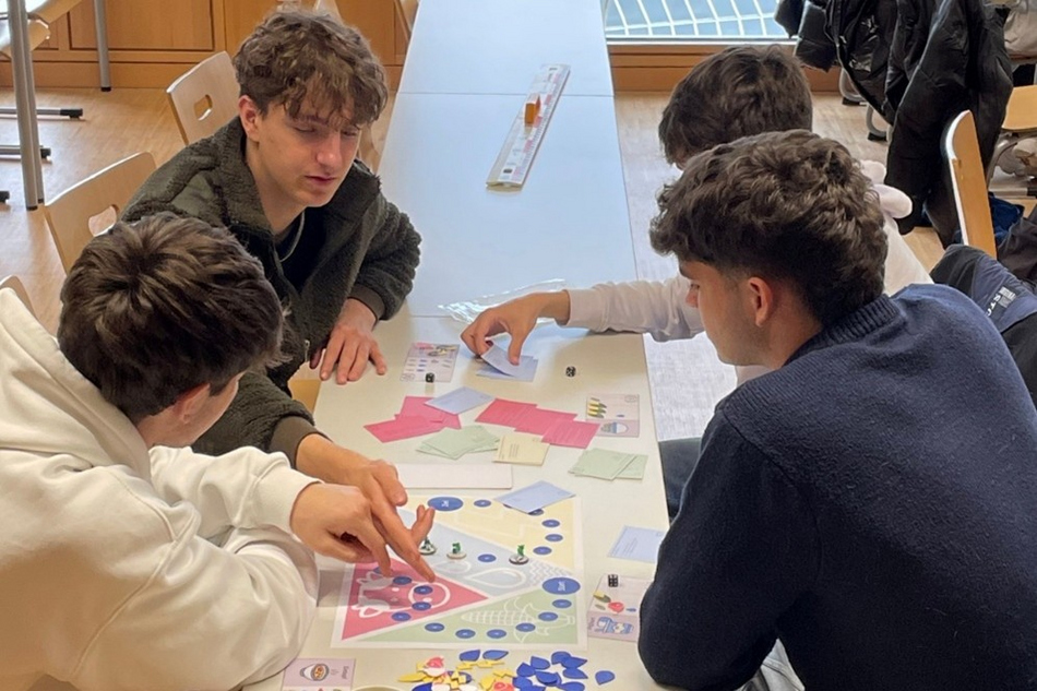 junge Menschen sitzen um einen Tisch und spielen ein Brettspiel